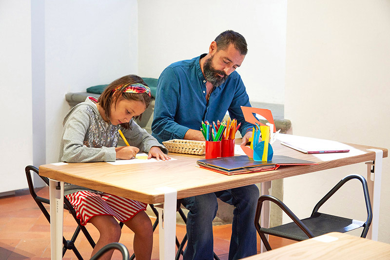 Attività laboratoriale al Maria Manetti Shrem Educational Center di Palazzo Strozzi con educatore e bambino seduti al tavolo mentre disegnano