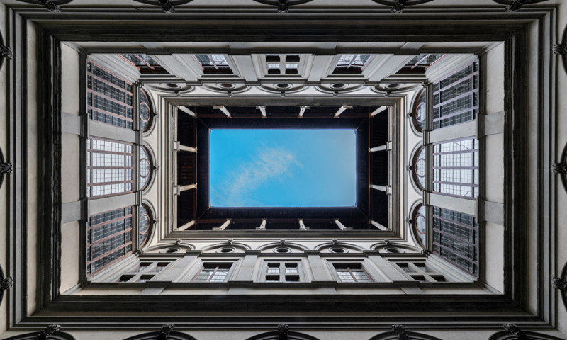 Vista dal basso del cortile di Palazzo Strozzi a Firenze con logge sovrapposte e cielo al centro