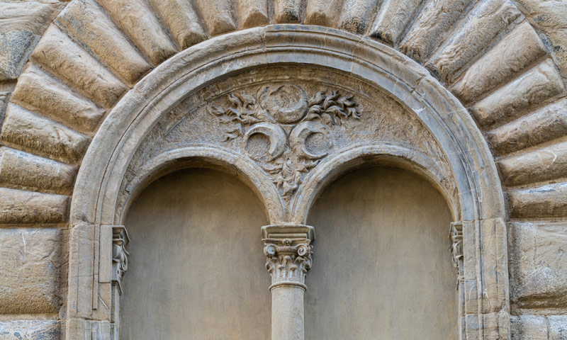 Dettaglio della bifora con arco decorato e capitello scolpito sulla facciata di Palazzo Strozzi a Firenze
